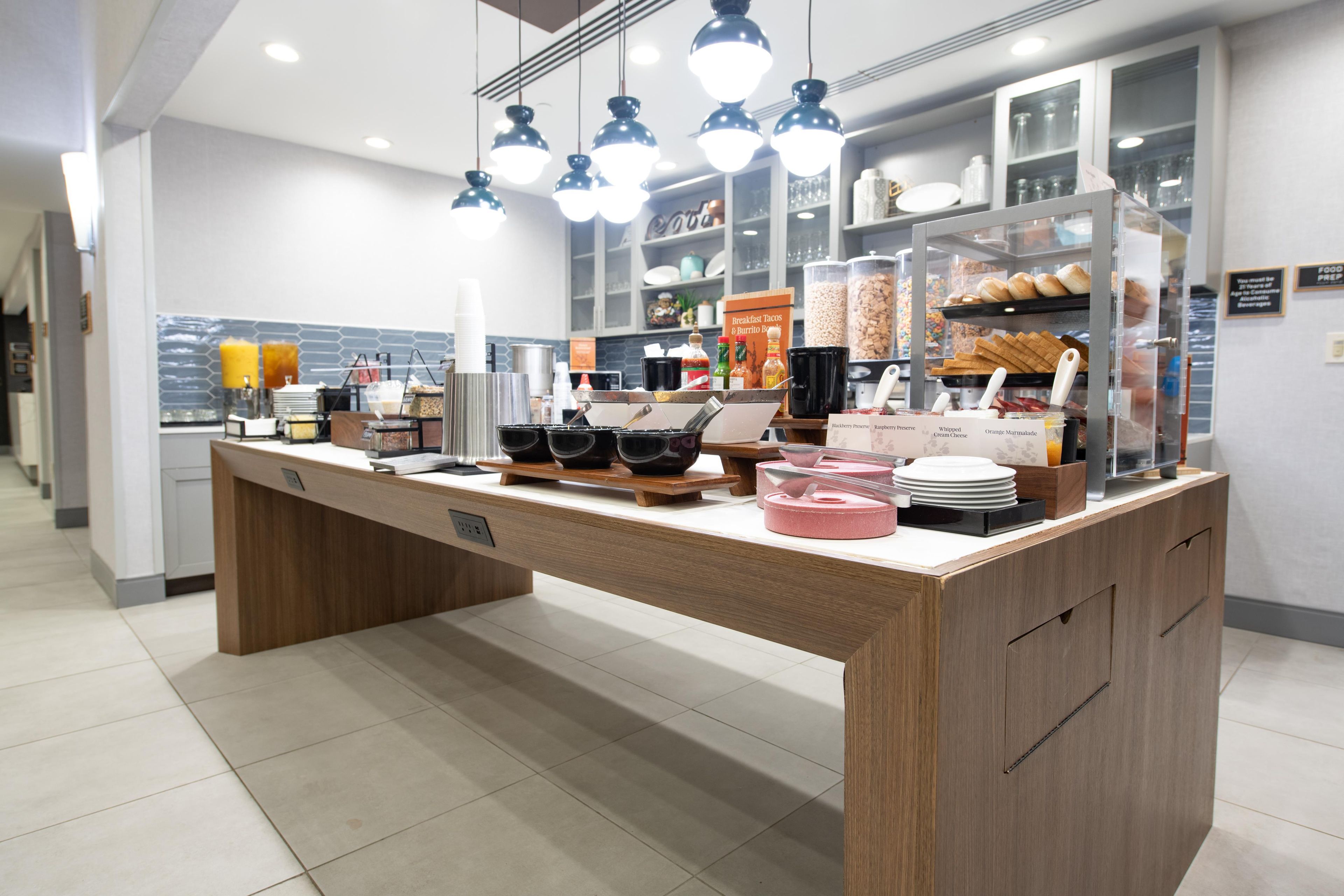 A breakfast bar with a variety of food items and condiments.