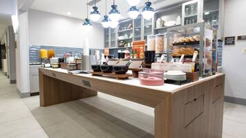 A breakfast bar with a variety of food items and condiments.
