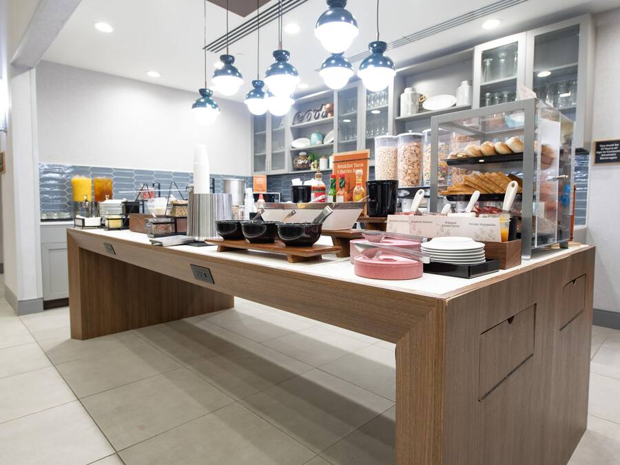 A breakfast bar with a variety of food items and condiments.
