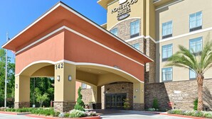 A hotel entrance with a covered driveway, a sign reading "Homewood Suites Hilton," and a number "142" on the building. - Homewood Suites Houma, La (Houma)