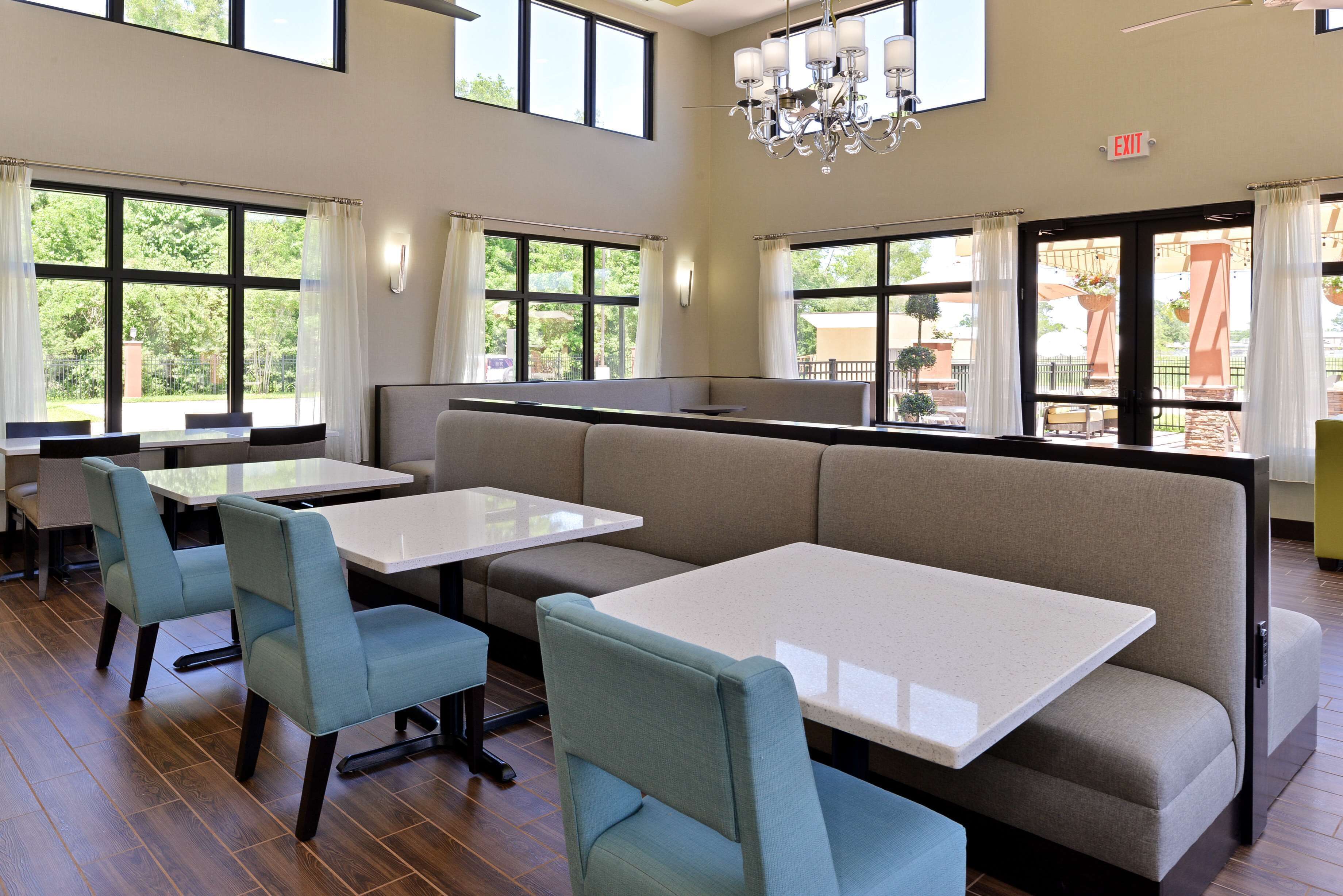 Un espace repas avec des tables et des chaises, de grandes fenêtres et un panneau indiquant la sortie.