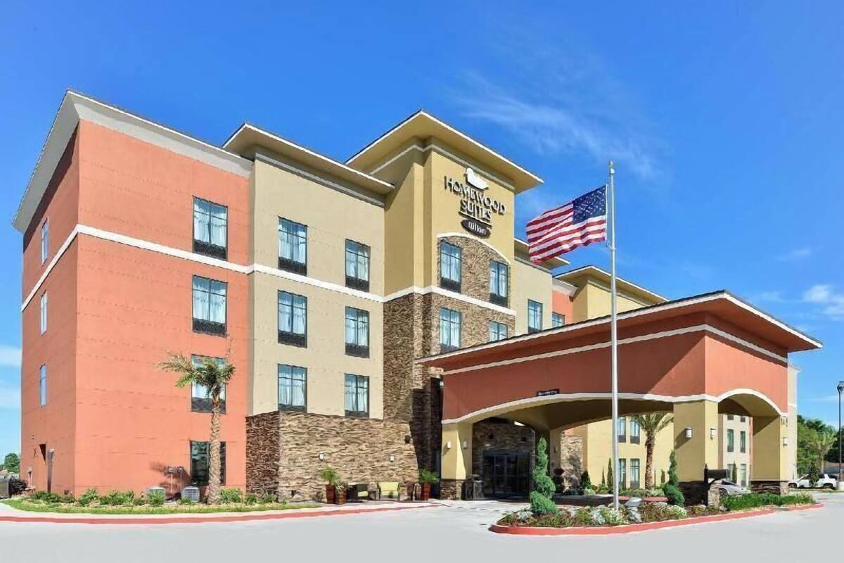 A multi-story hotel with a stone facade, an American flag, and a covered entrance.