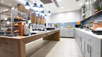 A modern kitchen with a central island, a coffee station, and a stone accent wall.