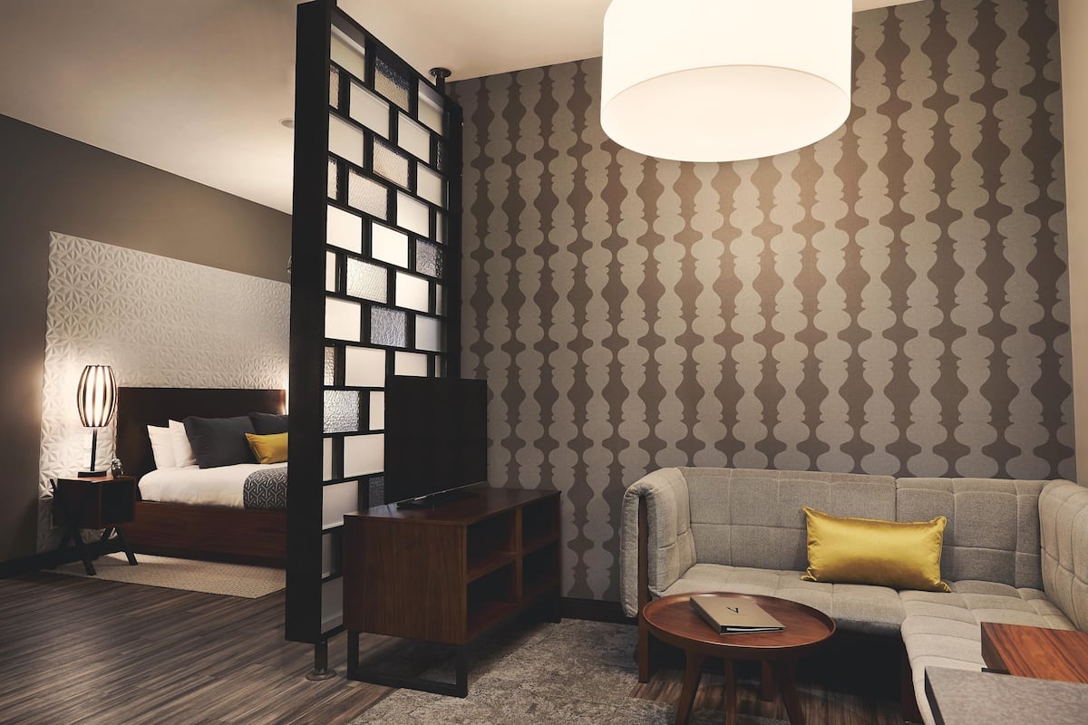 Ett modernt hotellrum med en säng, en soffa, ett soffbord och en tv.
