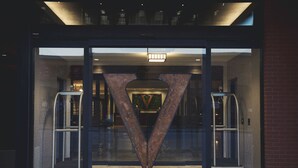 A hotel entrance with a large glass door, a metal structure in the center, and a sign reading "HOTEL VANDIVORT".