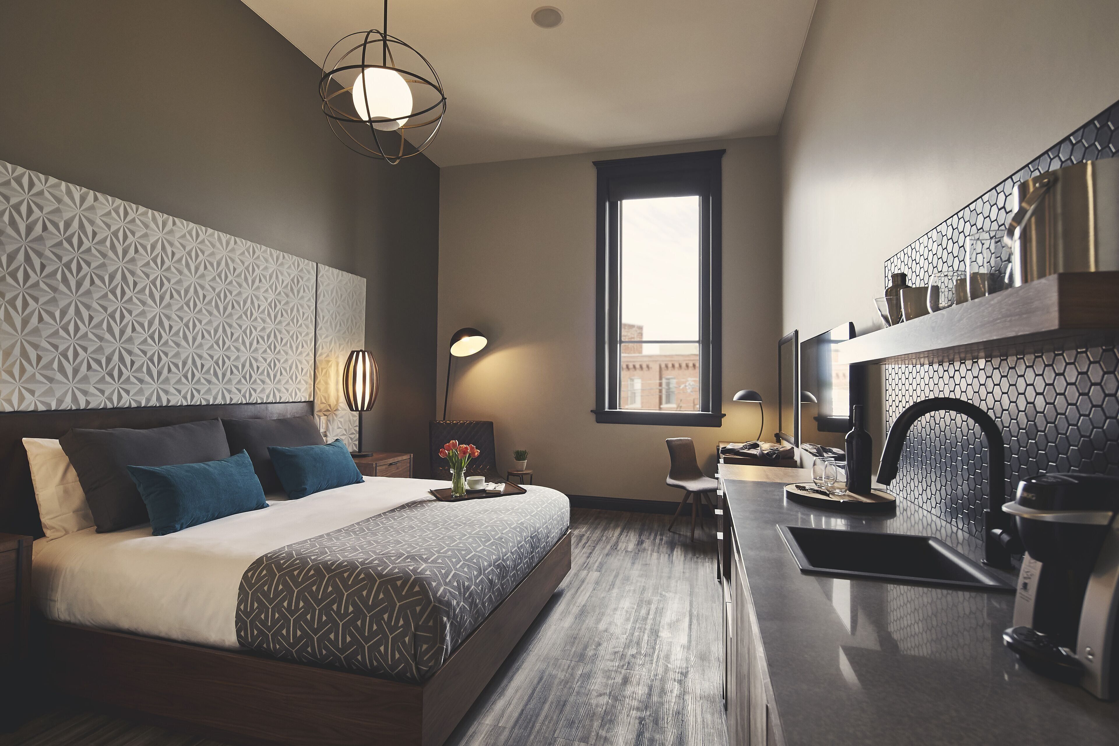 Een moderne hotelkamer met een groot bed, een bureau, een koffieapparaat en uitzicht op de stad door een raam.