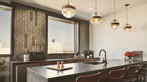 Una cocina moderna con una isla grande, taburetes de bar, un ventanal con vista a la ciudad e iluminación colgante.