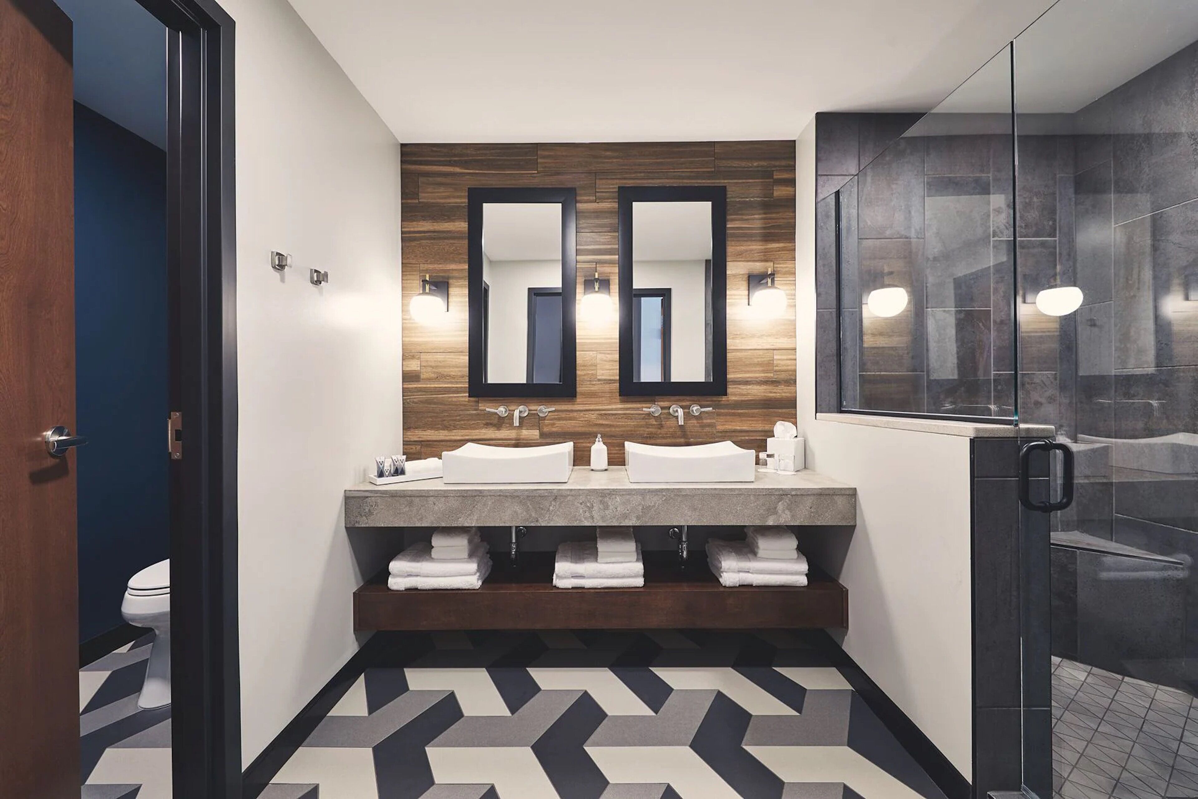 A modern bathroom with two sinks, a mirror, and a shower.