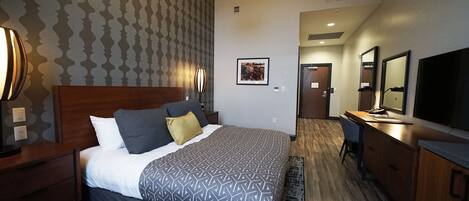 A hotel room with a bed, a desk, a TV, and a mirror.