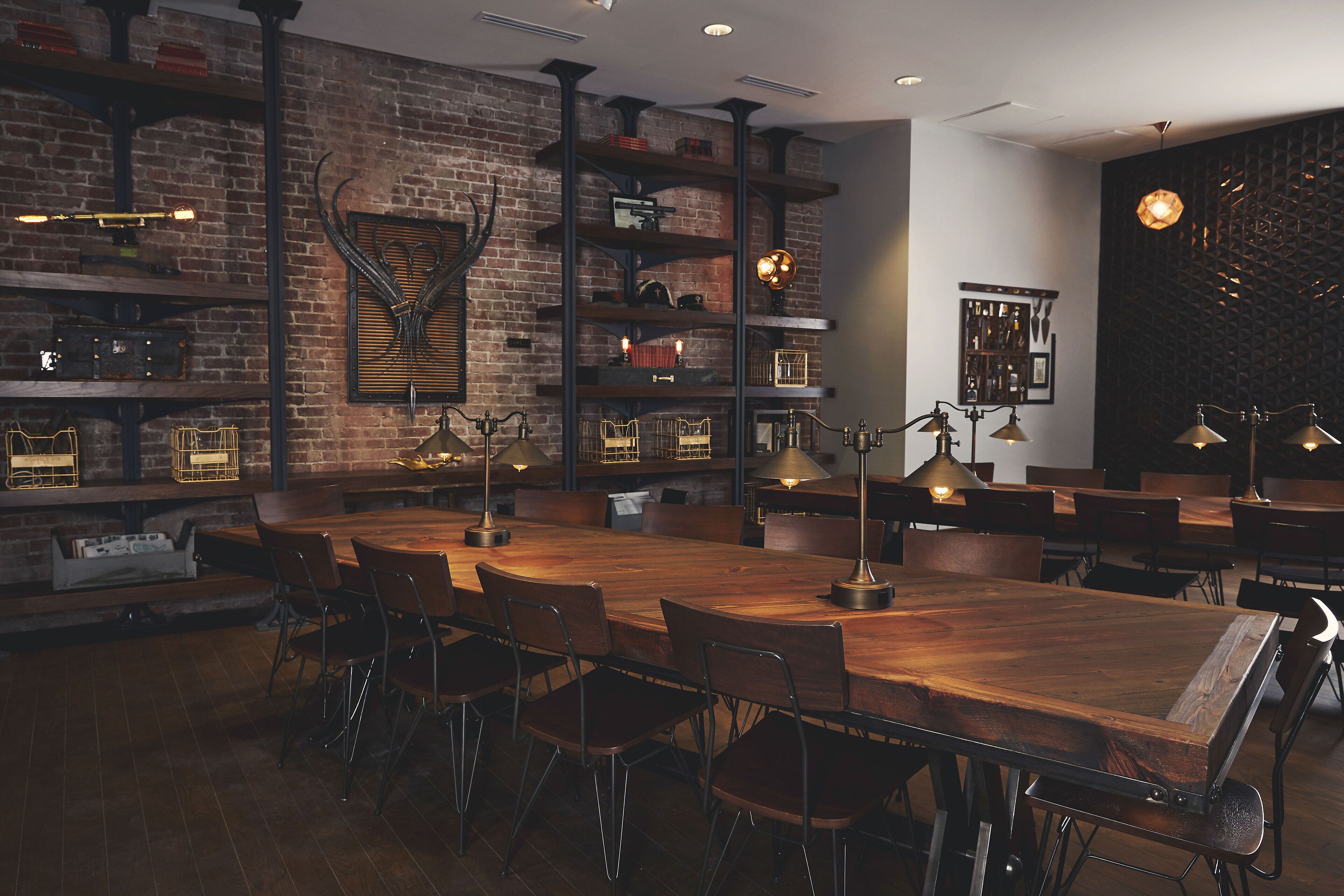 Un restaurante con pared de ladrillo rústico, mesas de madera y sillas de metal.