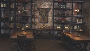 A dining area with a brick wall, metal shelves, and a central table with chairs.