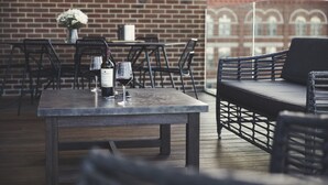 An outdoor seating area with a table set for two, featuring a bottle of wine and glasses.