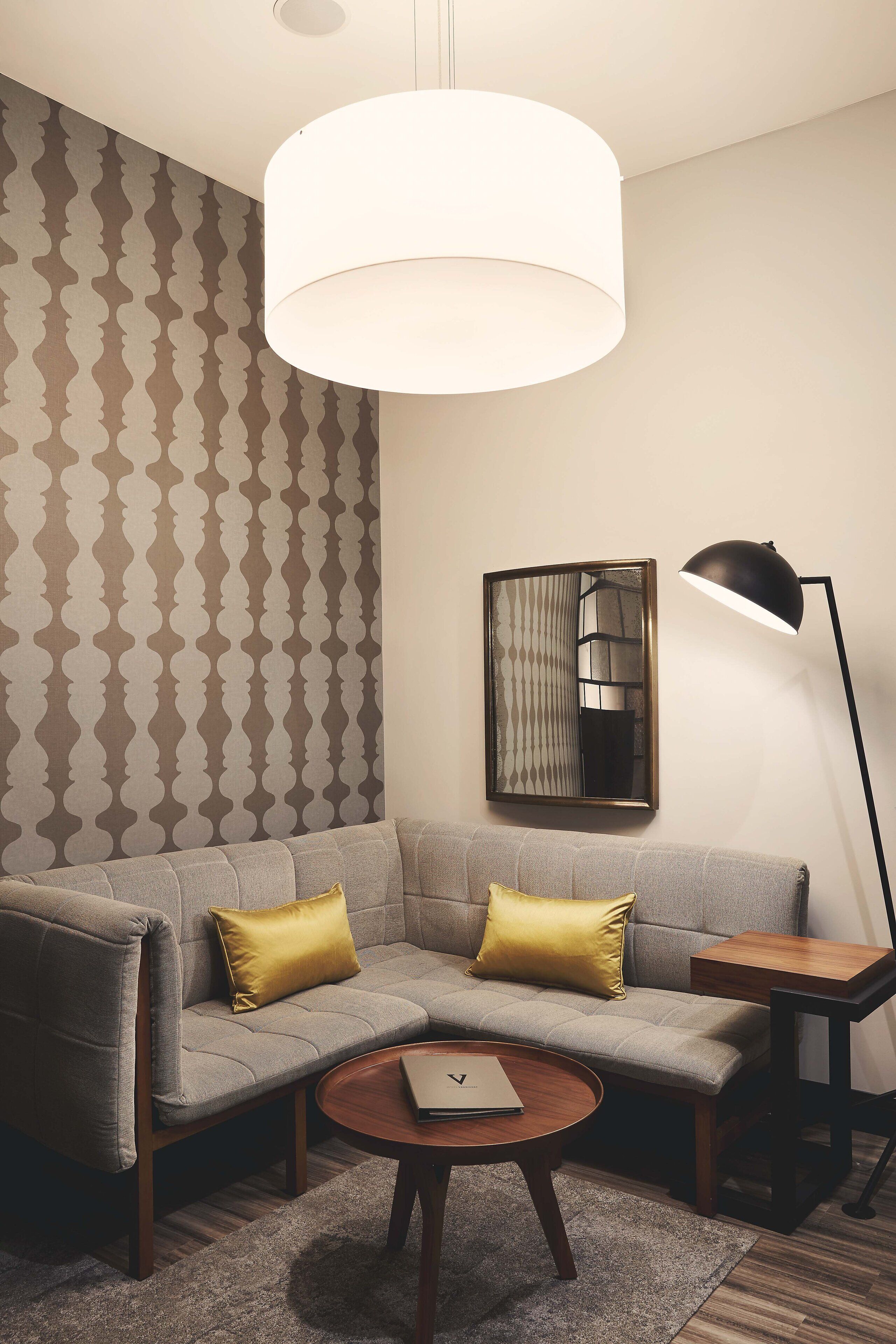 A modern living room with a sectional sofa, a round coffee table, a floor lamp, and a wall-mounted artwork.