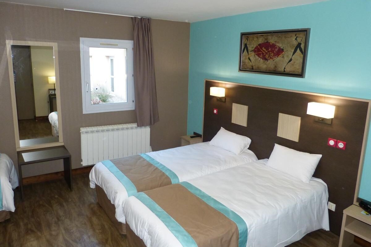 Habitación de hotel con cama doble, mesita de noche, espejo, ventana con cortinas y un cuadro colgado en la pared.