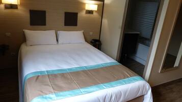 Een hotelkamer met een groot bed, twee bedlampen en een spiegel aan de muur.