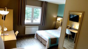 A hotel room with a bed, desk, chair, and a TV. - Hôtel Arbor (Mulsanne)