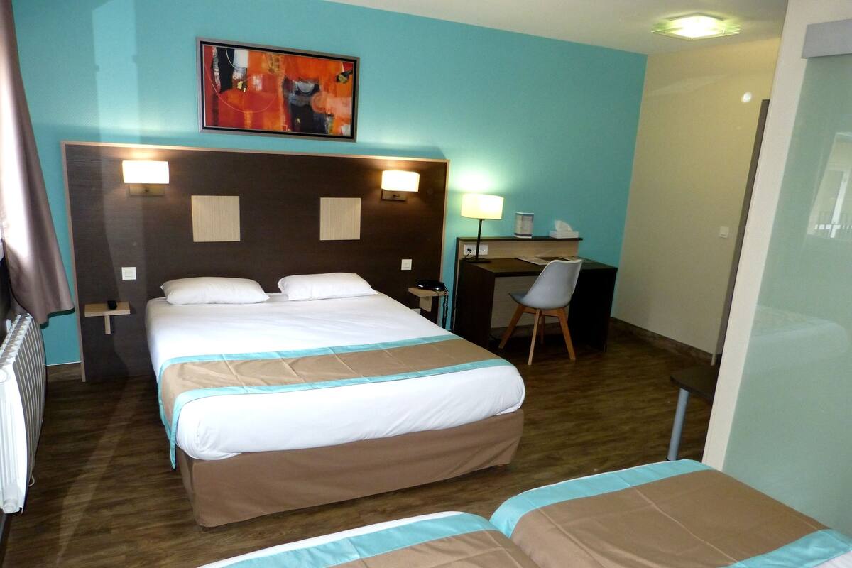 A hotel room with a large bed, a desk, and a chair.