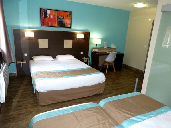A hotel room with a large bed, a desk, and a chair.