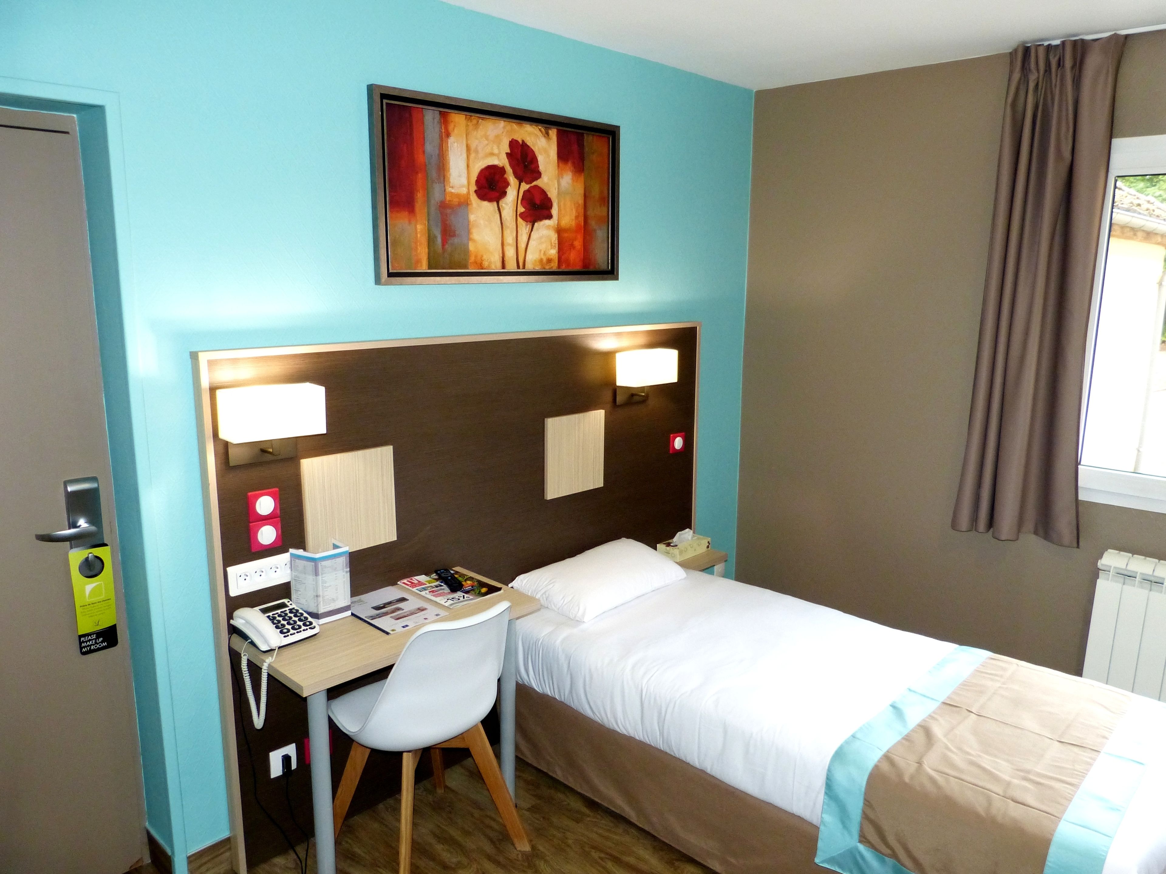 Une chambre d’hôtel avec un lit, un bureau, une chaise et un tableau au mur.