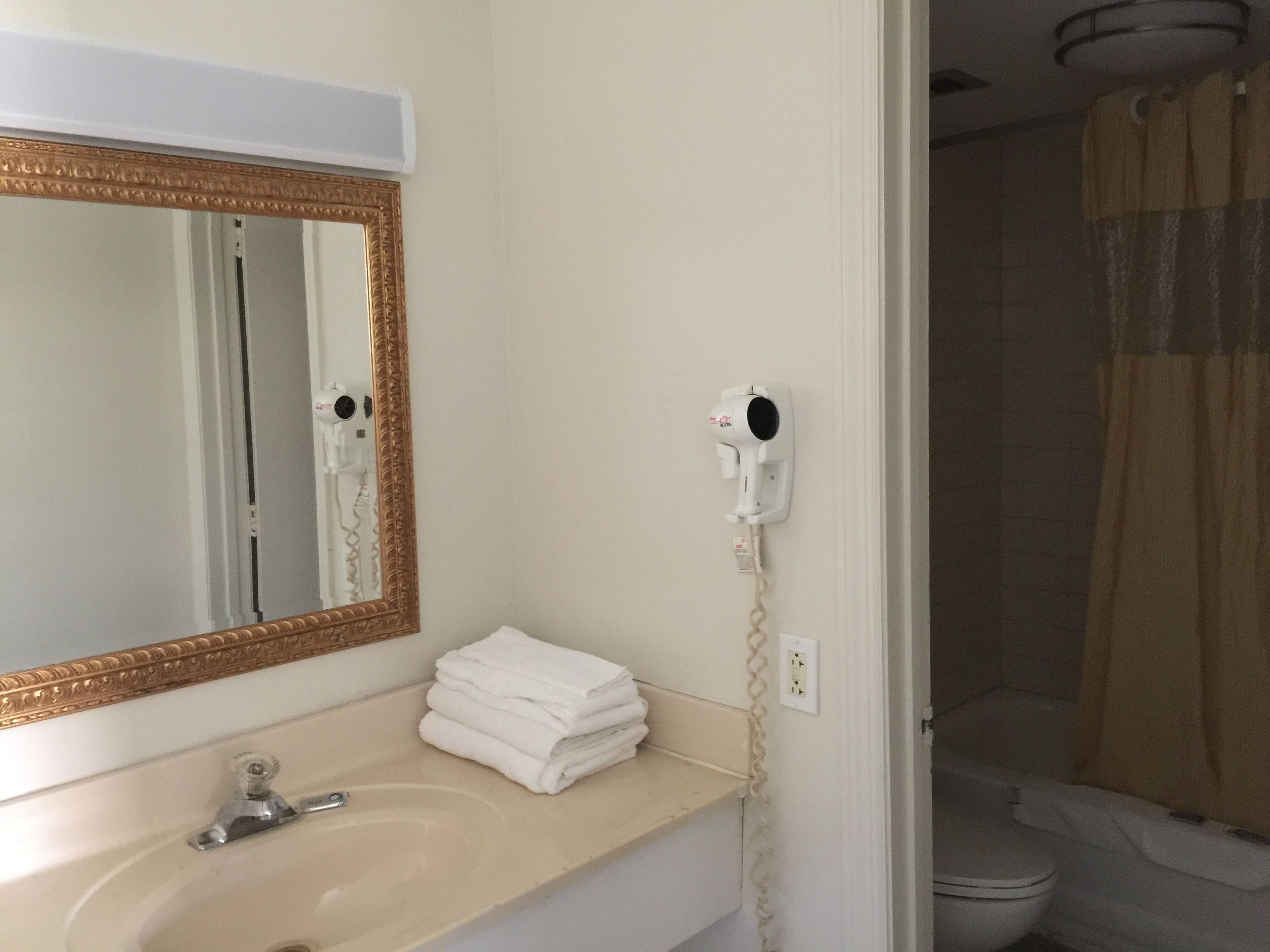 A bathroom with a sink, mirror, and hairdryer on the wall.