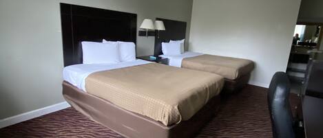 A hotel room with two beds, a desk, and a chair.