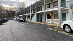 A multi-story parking garage with a row of parked cars and a building with balconies and a stairway. - Red Carpet Inn & Suites (Danville)