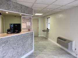 Uma área de recepção com balcão de mármore, um computador e um aviso de proibido fumar.