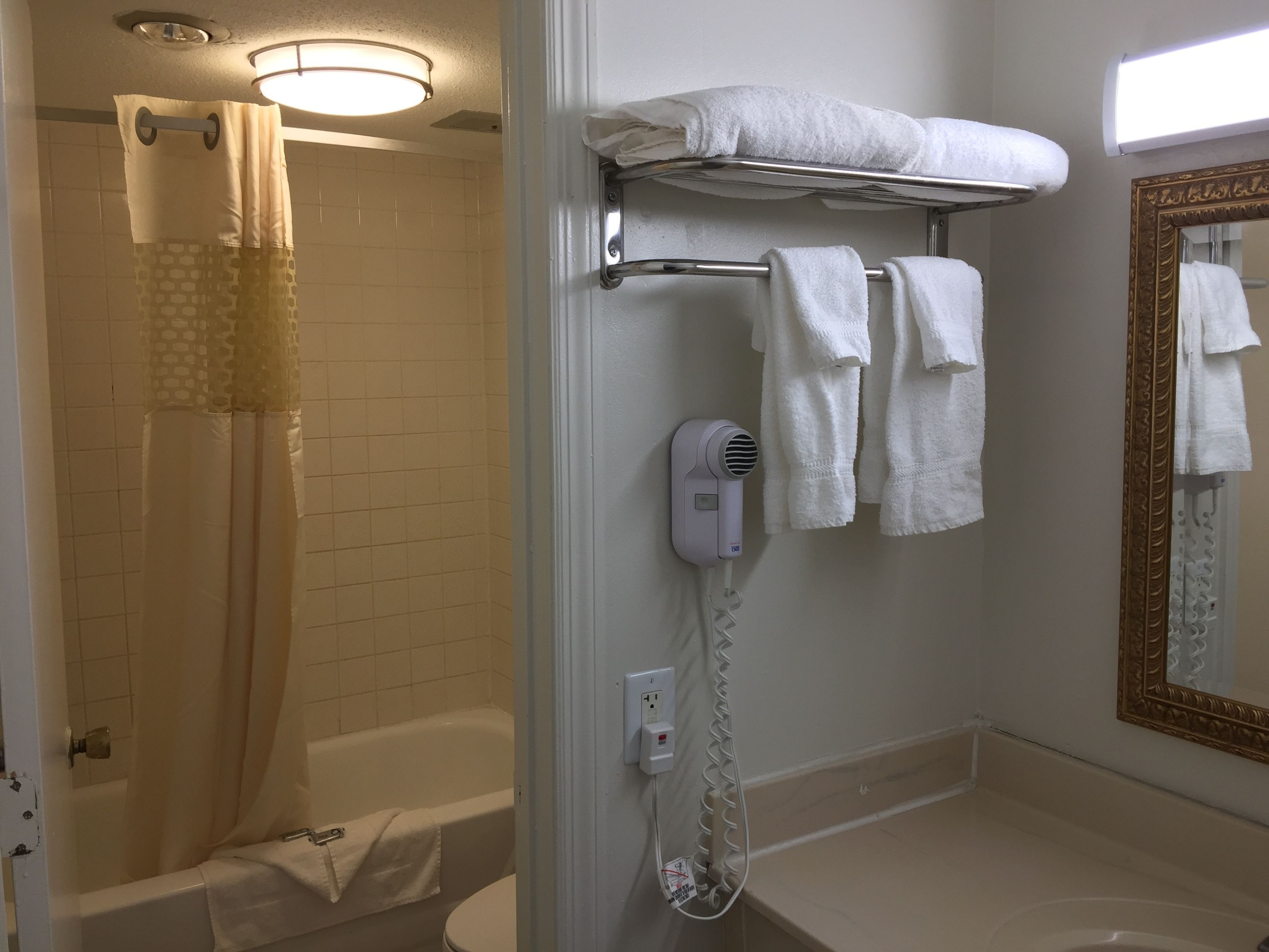 A bathroom with a shower, a bathtub, a toilet, a hairdryer, and a towel rack.