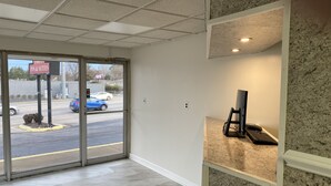 A hotel lobby with a reception desk, a computer on a stand, and a view of the street outside. - Red Carpet Inn & Suites (Danville)