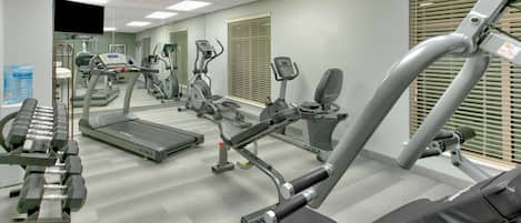 Un gimnasio con cintas de correr, elípticas y máquinas de pesas.