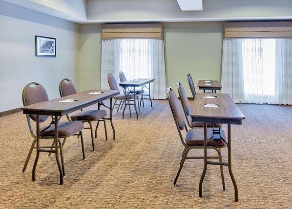 A conference room with a long table and chairs, carpeted floor, and large windows with curtains.