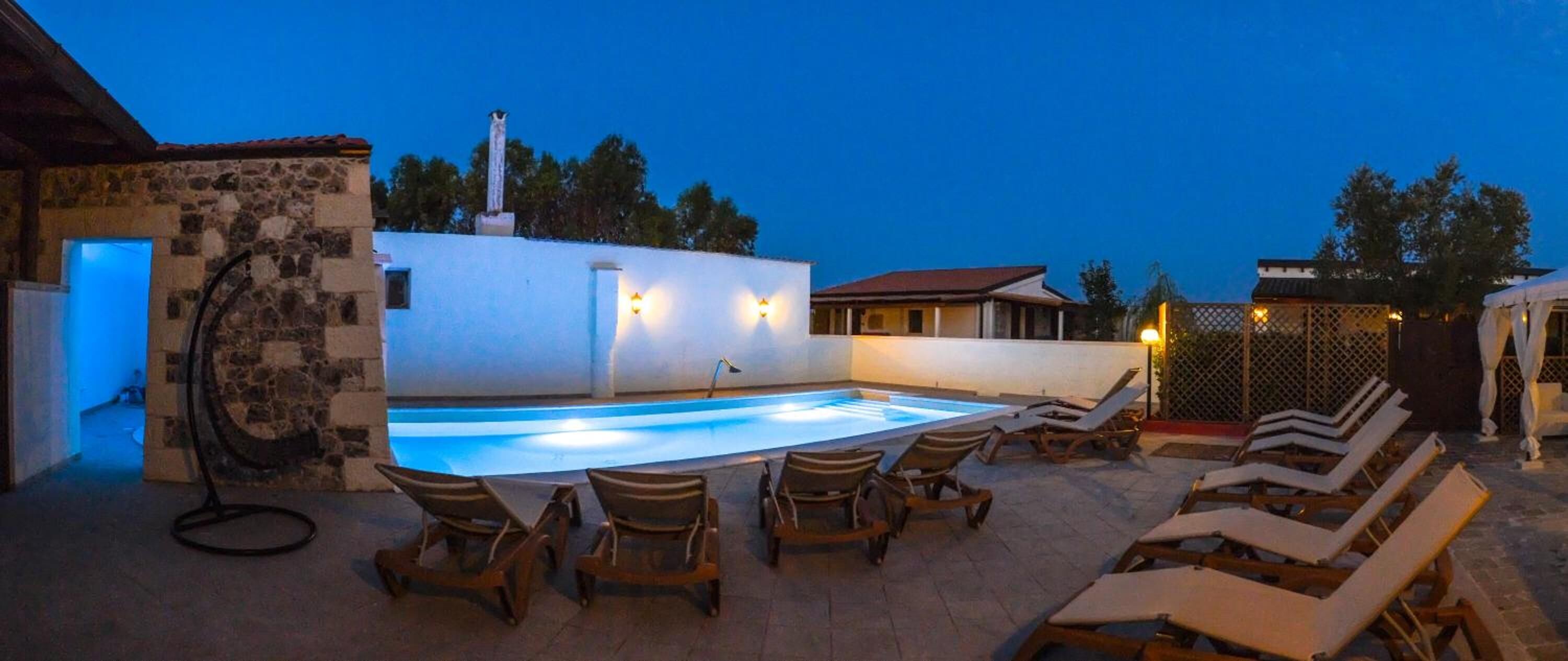 Une piscine extérieure avec des chaises longues et un mur en pierre.