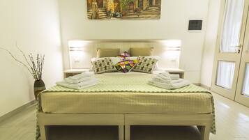 A neatly made bed with a quilted green and white bedspread, two pillows, and two folded towels.