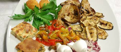 A plate of food with grilled vegetables, a slice of pie, and a side of chips.