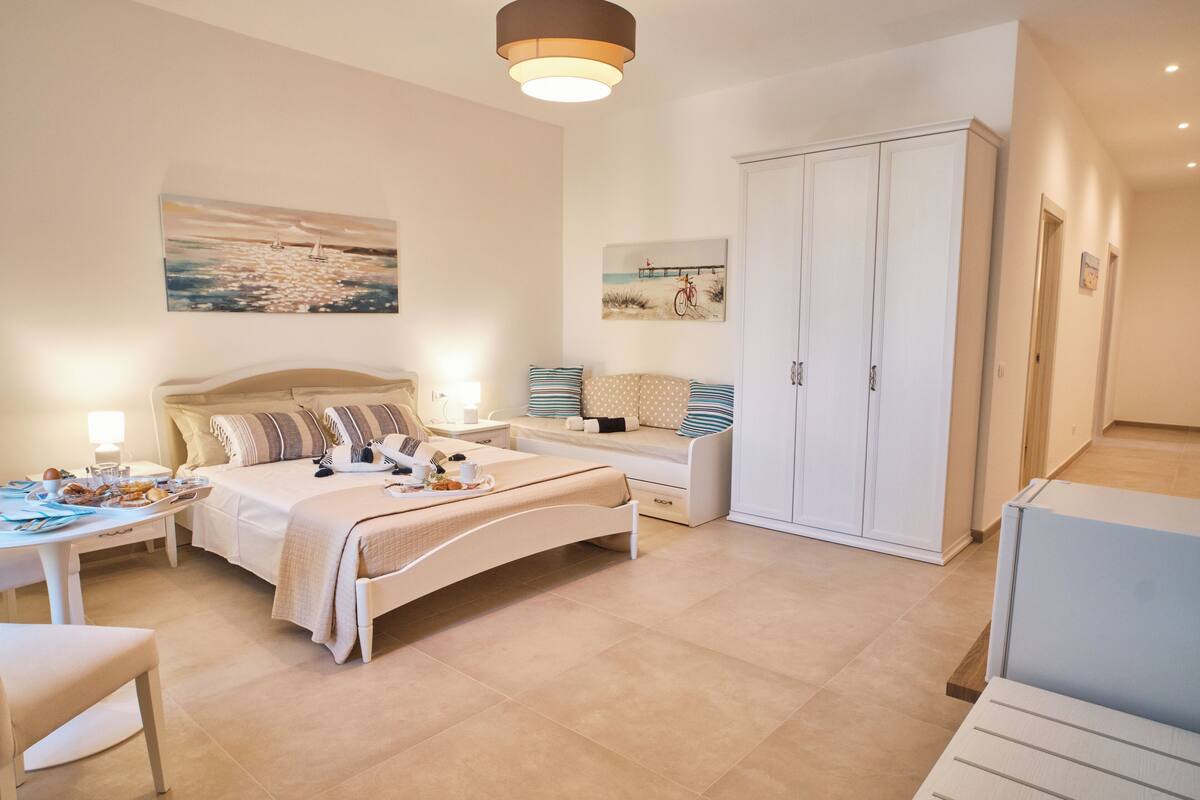A bedroom with a bed, bedside table, lamp, and artwork on the wall.