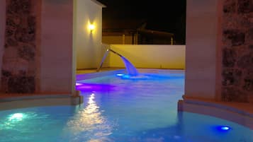 Zona de piscina con un arco de piedra y una fuente de agua.