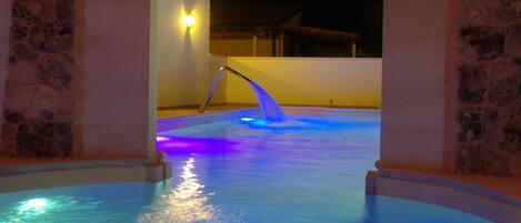 A pool area with a stone archway and a water feature.
