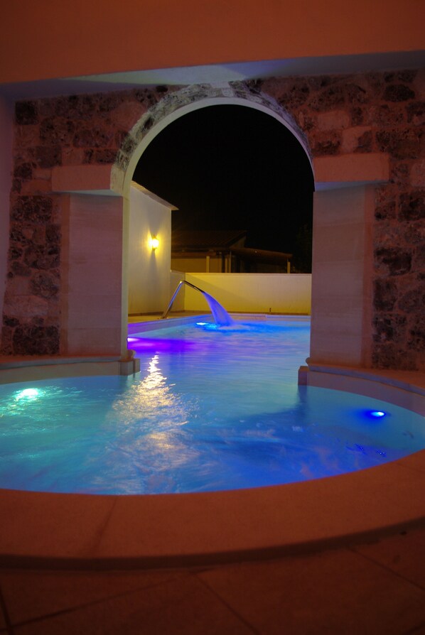 A pool area with a stone archway and a water feature.