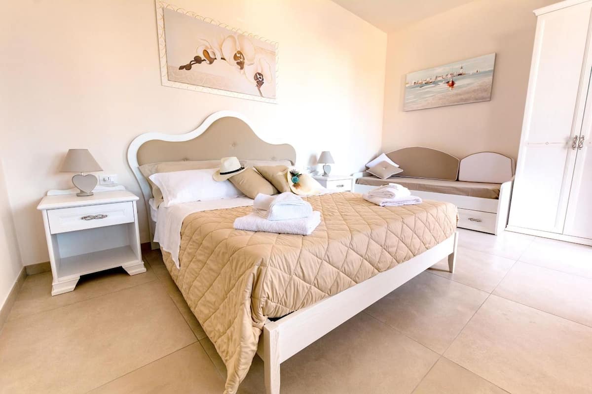 A bedroom with a bed, nightstands, a dresser, and artwork on the walls.