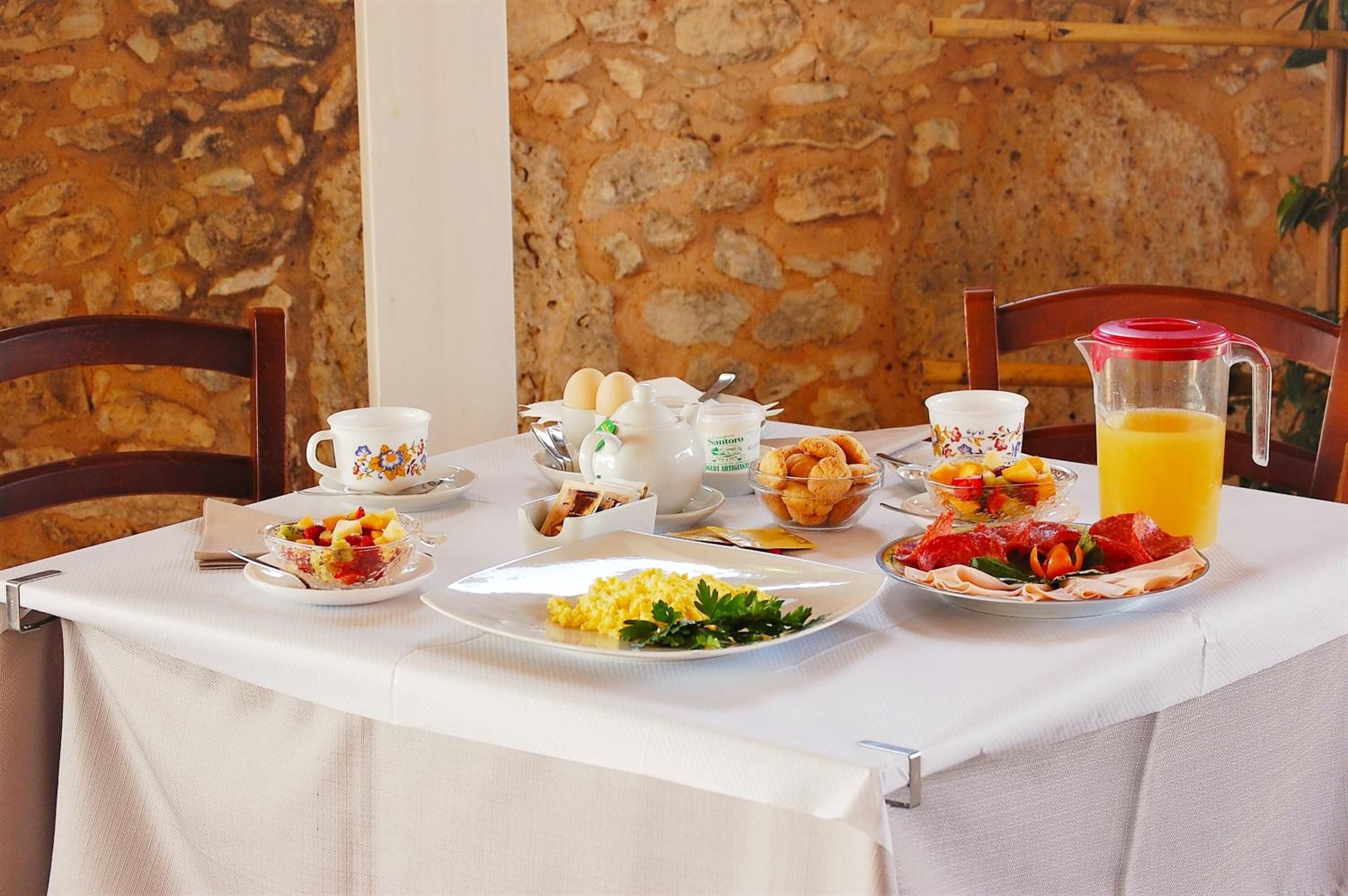 A breakfast table set with plates of food, a pitcher of orange juice, and a cup of coffee.