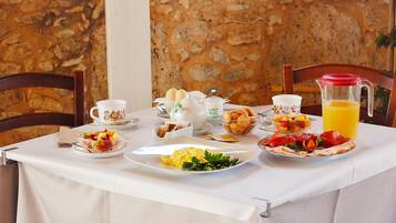 A breakfast table set with plates of food, a pitcher of orange juice, and a cup of coffee.