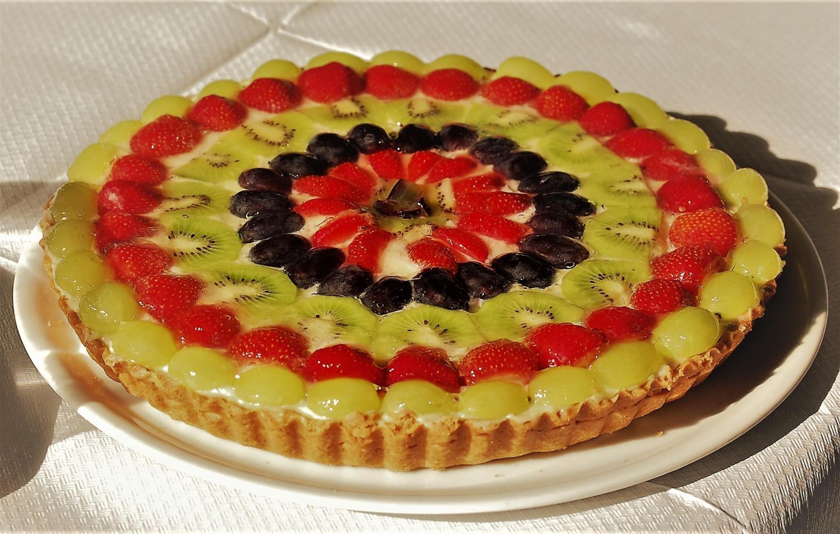 Una tarta redonda de frutas sobre un plato blanco.