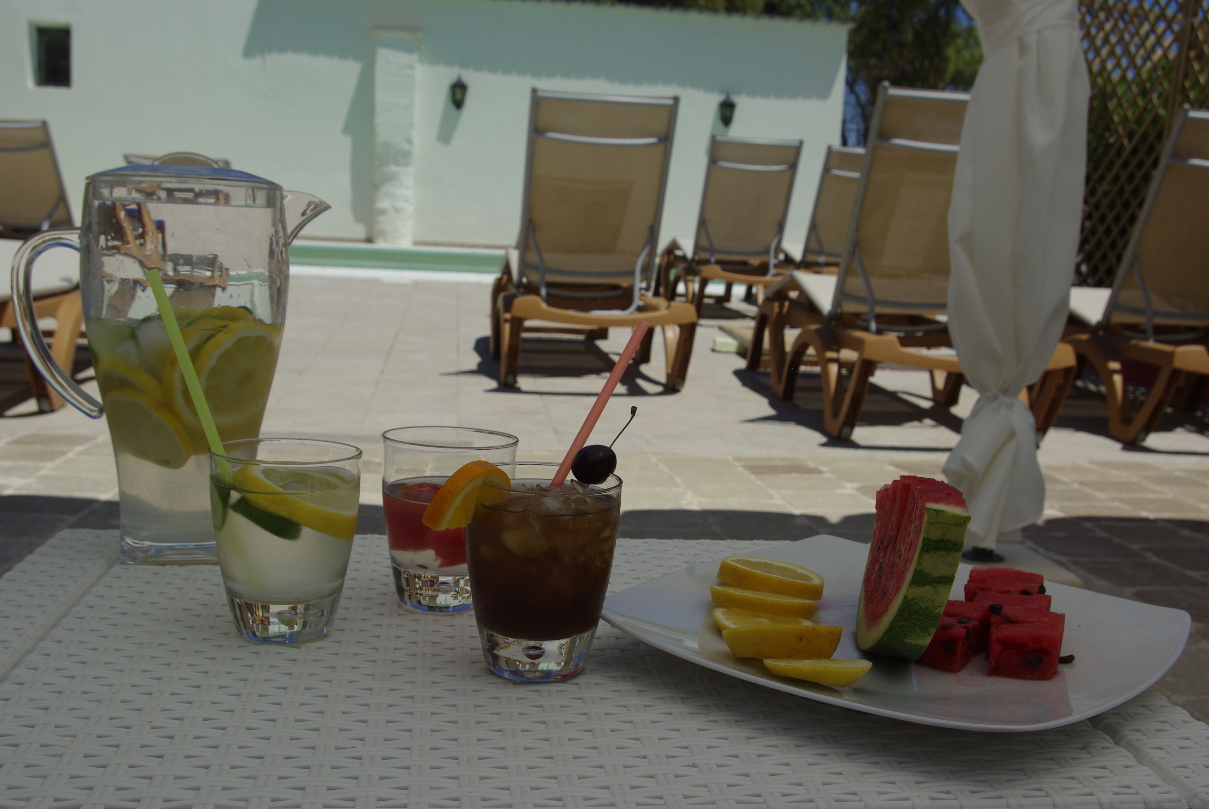 Une table avec une carafe, deux verres et une assiette contenant des tranches de pastèque et de citron.