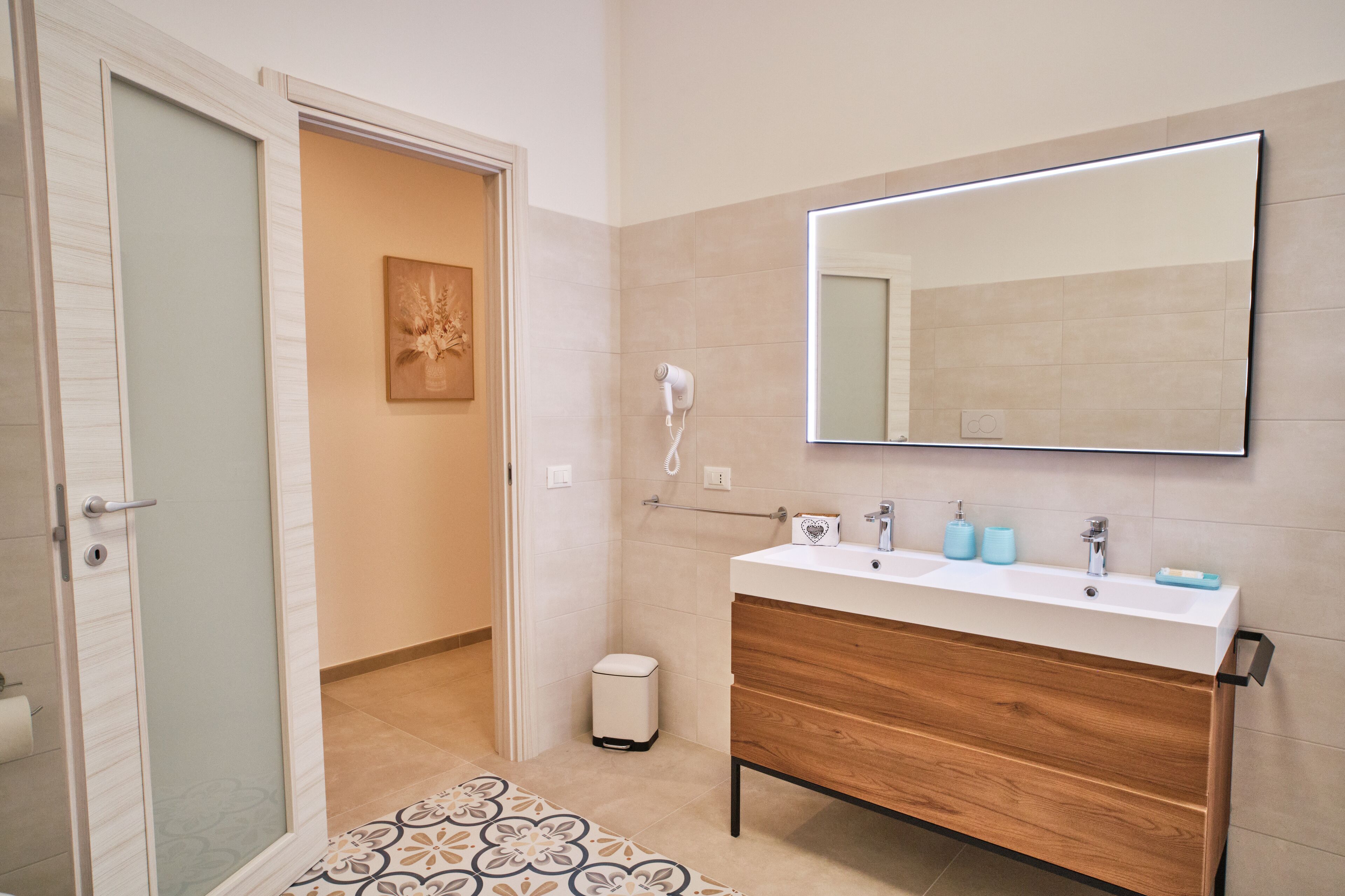 Un baño con tocador de madera, un espejo grande y zona de ducha.