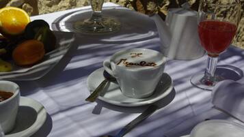 Ein Tisch mit einer weißen Tasse mit der Aufschrift 'Je Ne Regrette', einem Glas Rotwein und einer Fruchtschale.