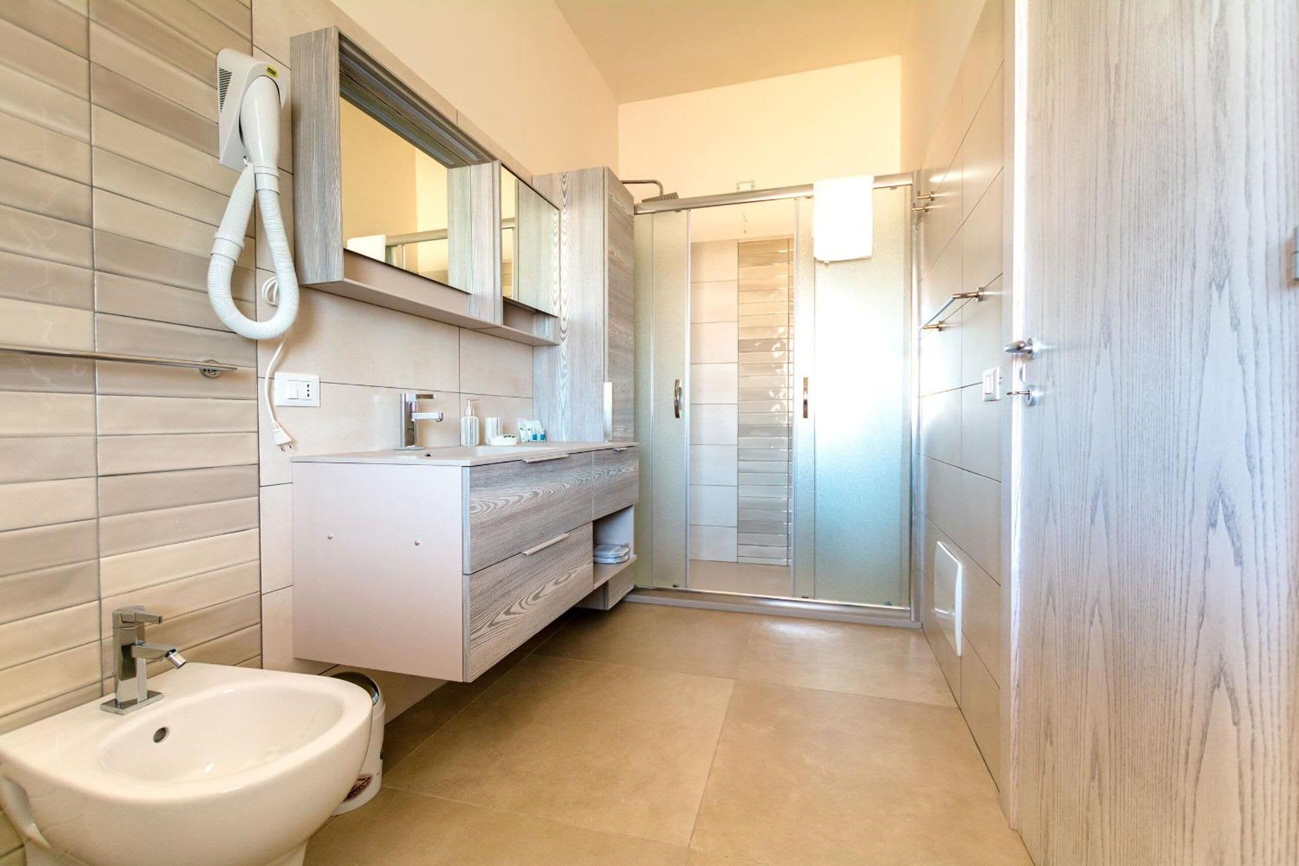 Un baño moderno con bidé, tocador, espejo y cabina de ducha.