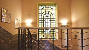 Un escalier avec une rampe en métal, un vitrail et un luminaire fixé au mur.