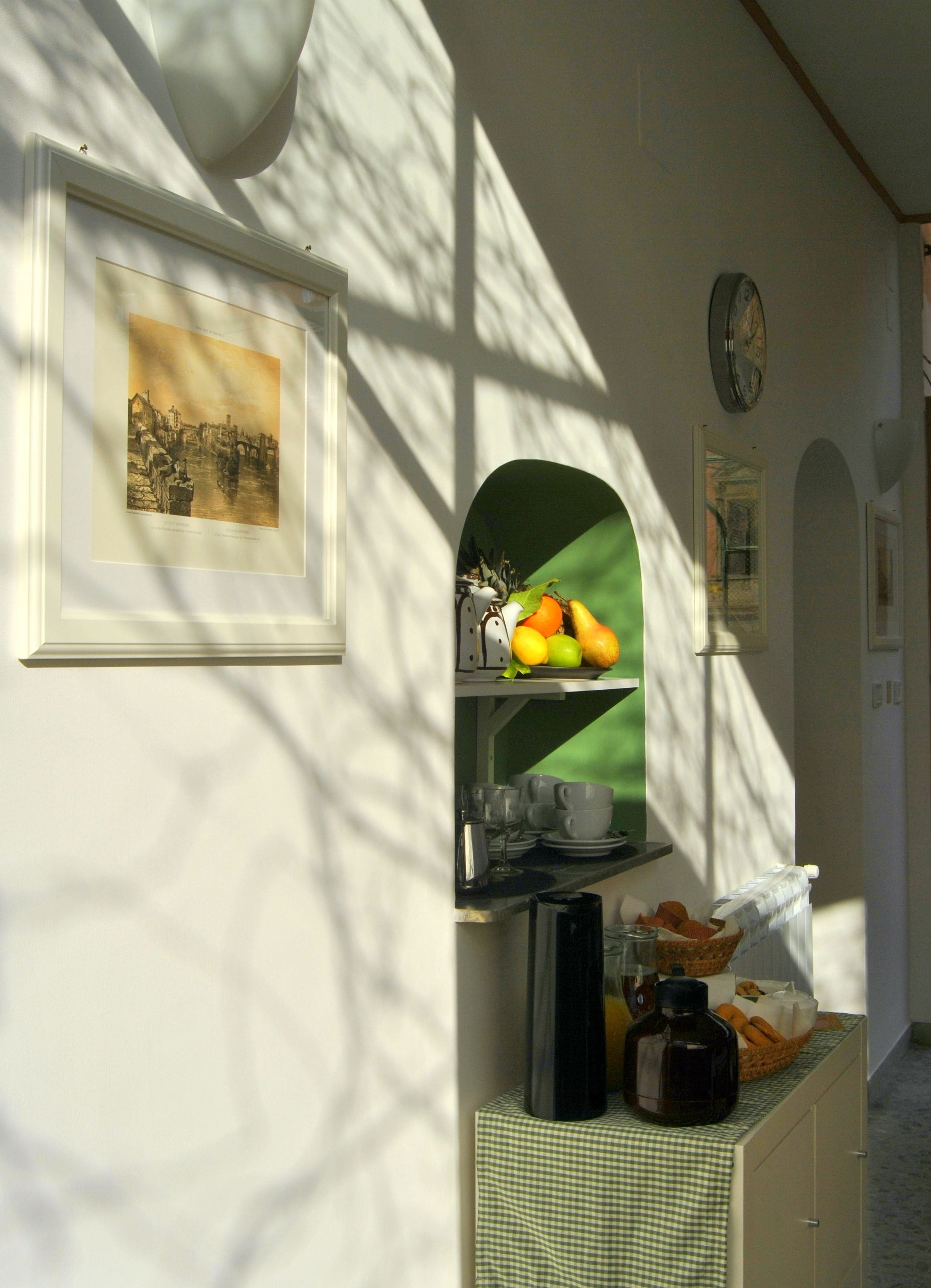 Un corridoio con un quadro incorniciato, una sveglia e un vassoio di frutta.