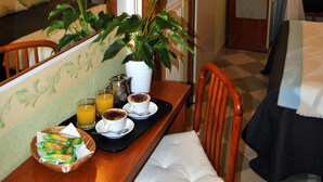 Une chambre d’hôtel comprenant un coin repas, un lit, une télévision et une fenêtre avec des rideaux.