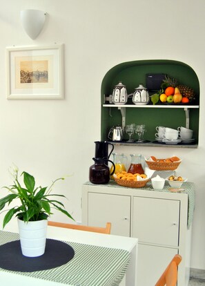 A kitchen with a green archway, a framed picture on the wall, and a table with a potted plant.